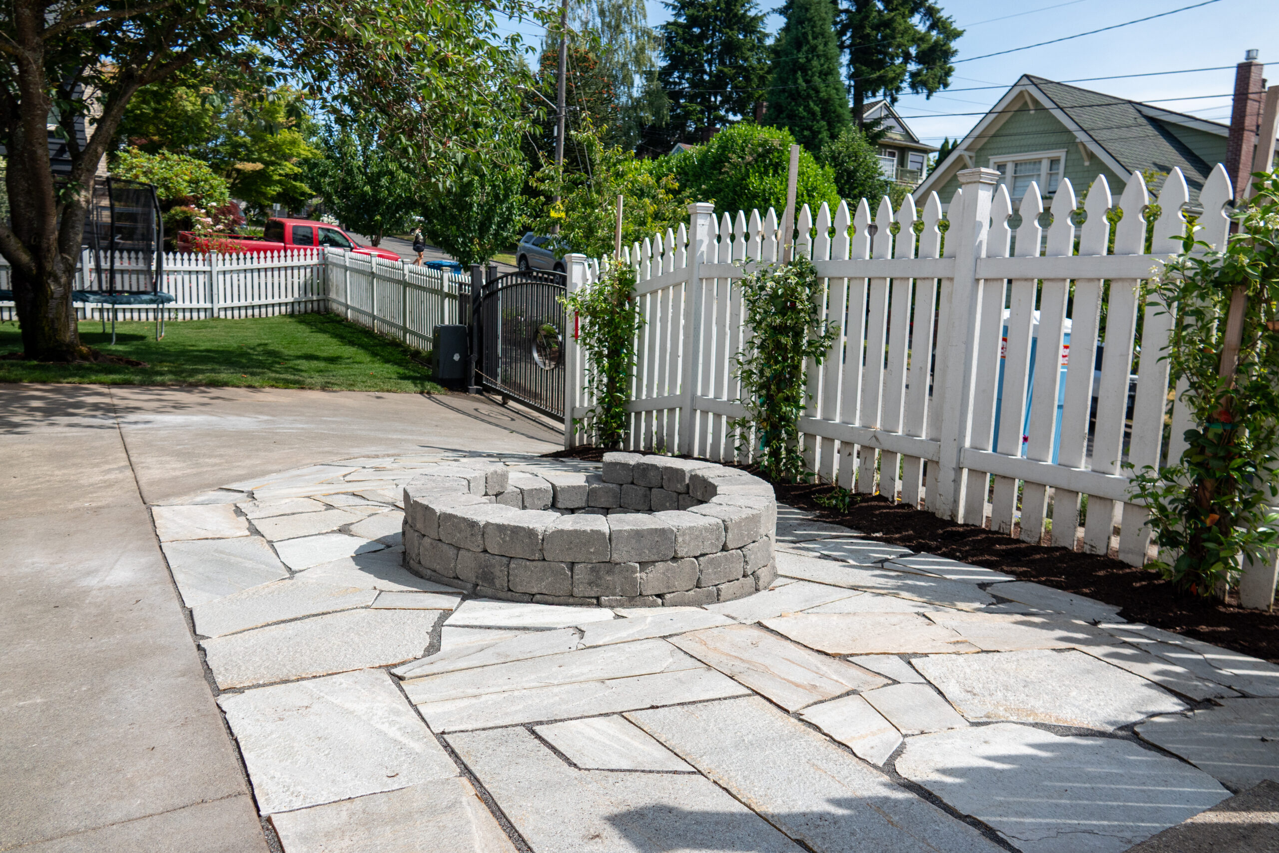White picket fence in a front yard right next to a fire pit